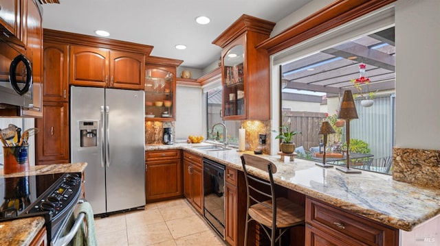 kitchen with glass insert cabinets, a sink, light stone countertops, plenty of natural light, and black appliances