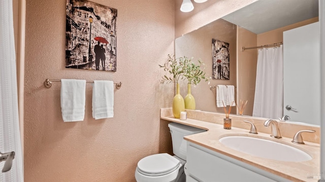 full bathroom featuring toilet, a textured wall, and vanity