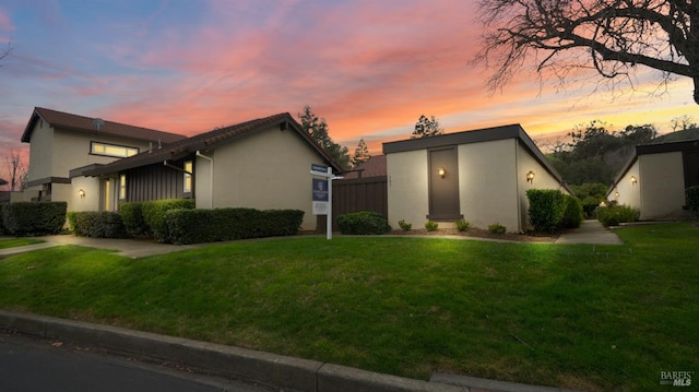 view of front of property with a front yard, fence, and stucco siding