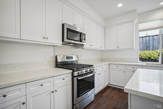 kitchen featuring dark wood-style flooring, recessed lighting, appliances with stainless steel finishes, white cabinetry, and a sink