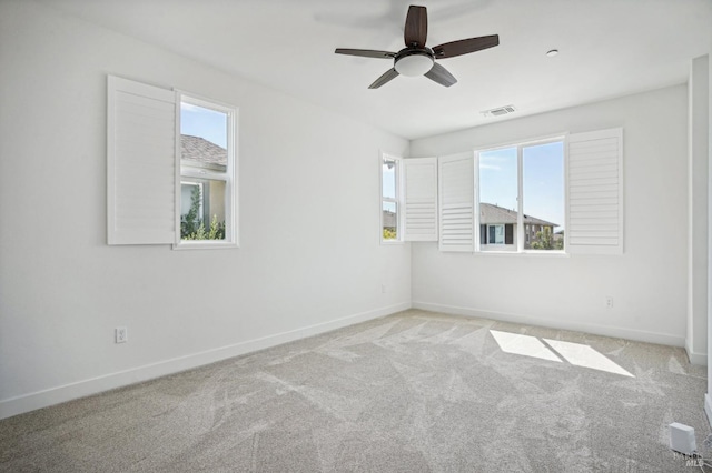 spare room featuring baseboards, a ceiling fan, visible vents, and light colored carpet