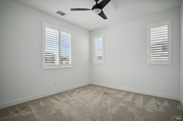 carpeted spare room with a ceiling fan, visible vents, and baseboards