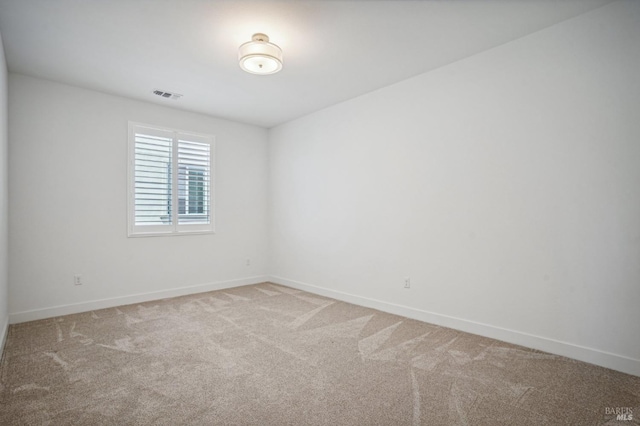 empty room featuring carpet floors, visible vents, and baseboards