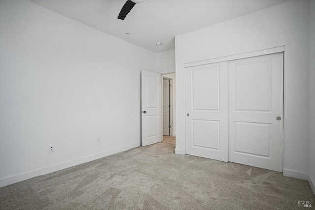 unfurnished bedroom featuring a closet, light colored carpet, and baseboards