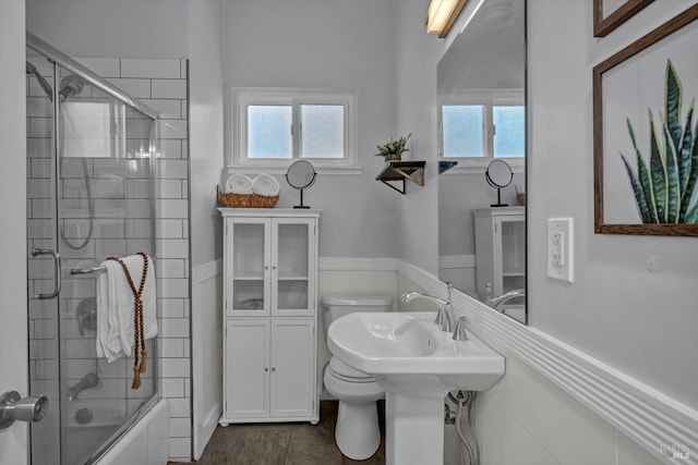 bathroom with toilet, plenty of natural light, and combined bath / shower with glass door