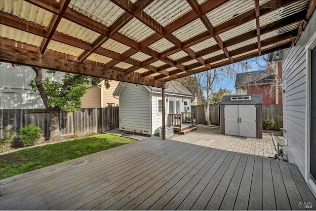 deck featuring a patio, a fenced backyard, a storage unit, a yard, and an outdoor structure