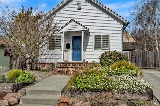 shotgun-style home featuring entry steps and fence