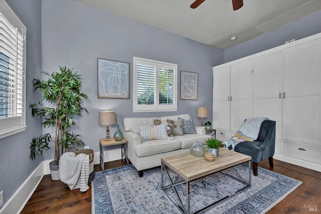 living room featuring a ceiling fan, baseboards, and dark wood-type flooring