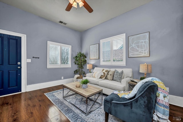 living area featuring a healthy amount of sunlight, baseboards, a ceiling fan, and dark wood-type flooring