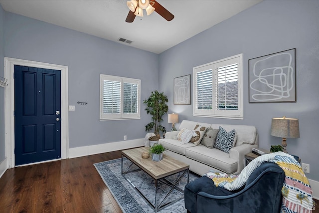 living room with baseboards, dark wood-type flooring, visible vents, and a ceiling fan