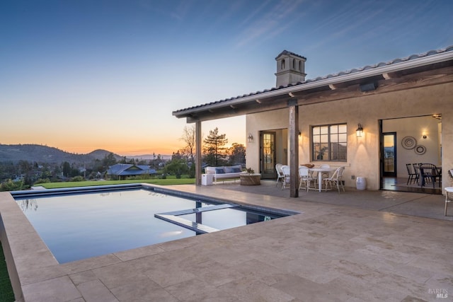 view of pool featuring a pool with connected hot tub, a patio area, and a mountain view