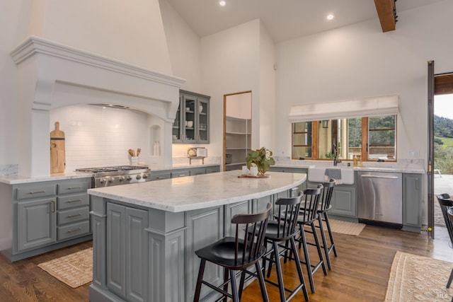 kitchen with a sink, a kitchen island, stainless steel dishwasher, and gray cabinetry