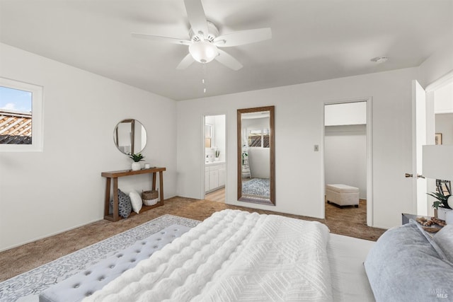 bedroom featuring light carpet, ceiling fan, a walk in closet, and connected bathroom