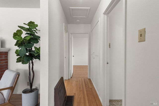 hall featuring light wood-style floors, attic access, and baseboards