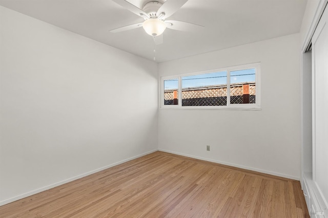 spare room with light wood finished floors, a ceiling fan, and baseboards