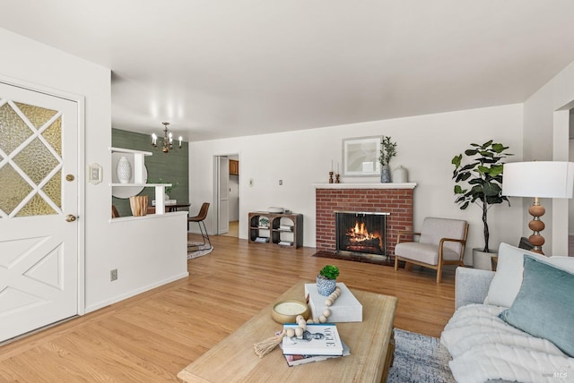 living room with a brick fireplace, a notable chandelier, and wood finished floors