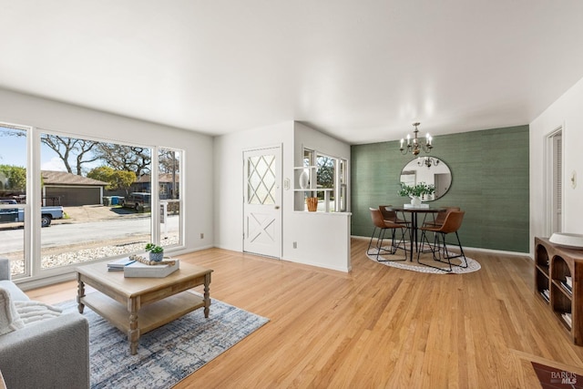 living area with an accent wall, a healthy amount of sunlight, wallpapered walls, and light wood-style floors