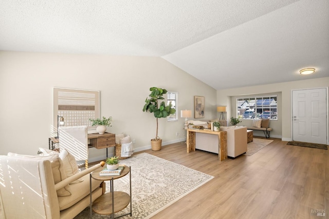 living area featuring light wood-type flooring, baseboards, and vaulted ceiling