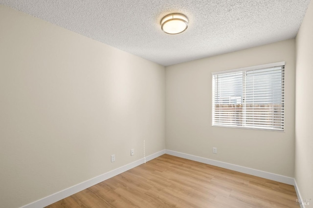 unfurnished room featuring light wood-style flooring, baseboards, and a textured ceiling