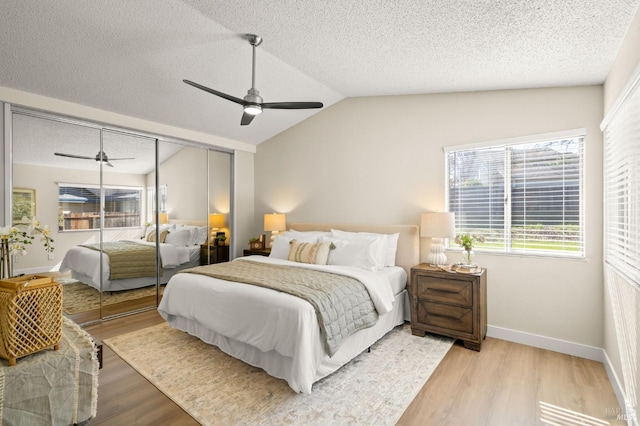 bedroom featuring light wood finished floors, baseboards, a ceiling fan, vaulted ceiling, and a textured ceiling