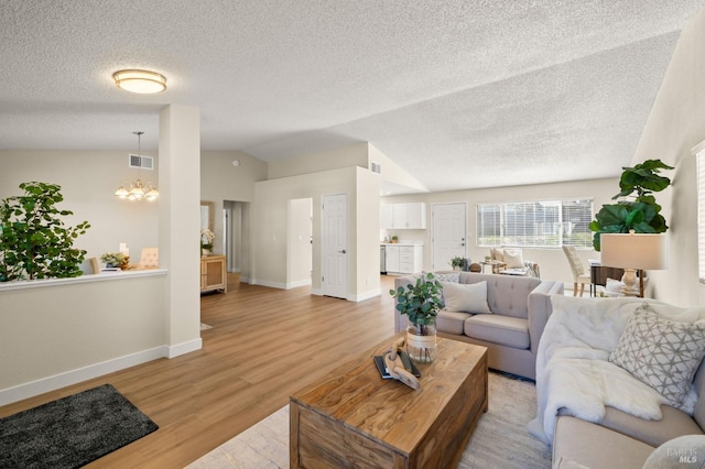 living area with a notable chandelier, lofted ceiling, visible vents, light wood-style flooring, and baseboards