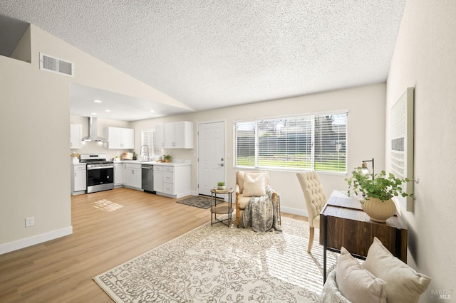 living area with lofted ceiling, light wood-style flooring, visible vents, and baseboards