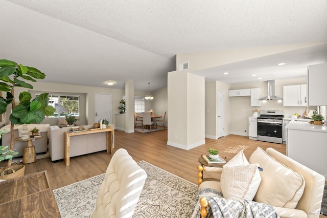 living room featuring a textured ceiling, light wood-style flooring, visible vents, baseboards, and vaulted ceiling