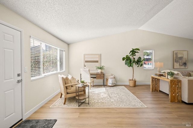 sitting room with lofted ceiling, light wood finished floors, and plenty of natural light