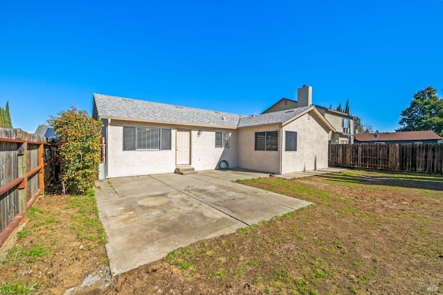 rear view of house featuring a yard, a patio, a chimney, stucco siding, and a fenced backyard