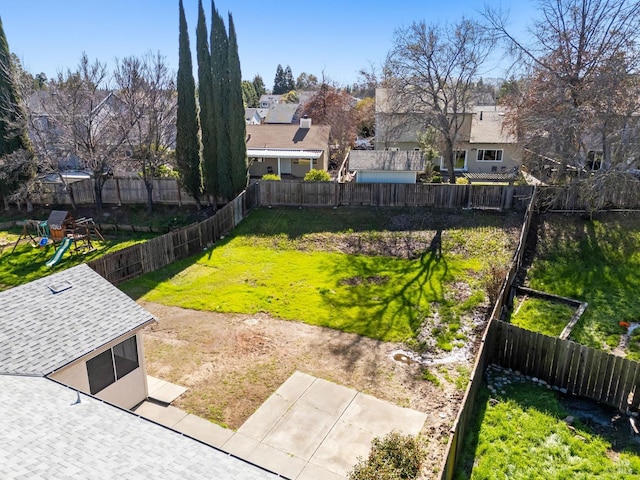 view of yard featuring a residential view, a fenced backyard, and a playground