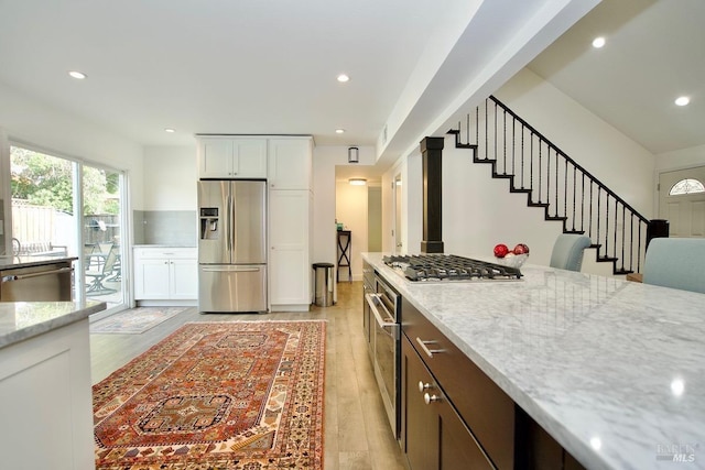 kitchen featuring stainless steel appliances, white cabinetry, and light stone countertops