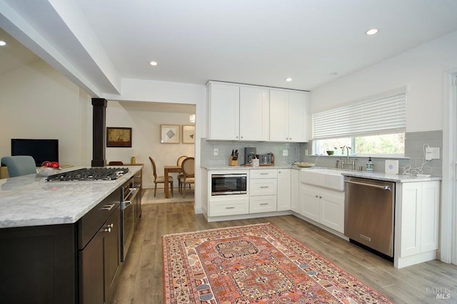 kitchen featuring decorative backsplash, white cabinetry, stainless steel appliances, and a sink