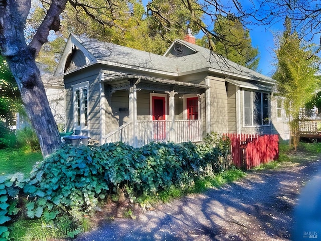 view of side of property featuring covered porch and a chimney