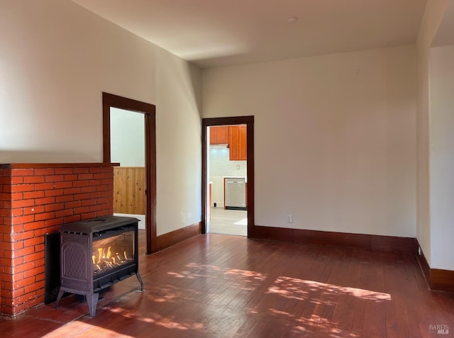 unfurnished living room with a wood stove, baseboards, and dark wood-type flooring