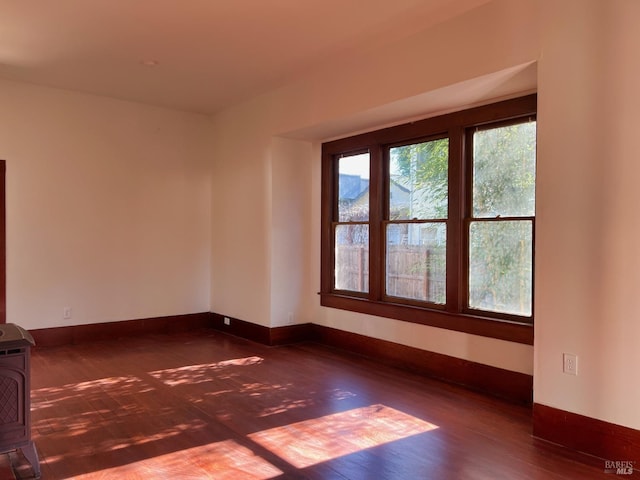 spare room with baseboards and dark wood finished floors