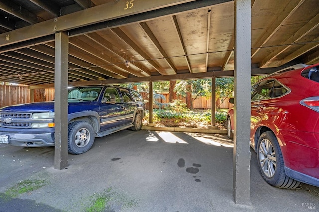 covered parking lot featuring fence