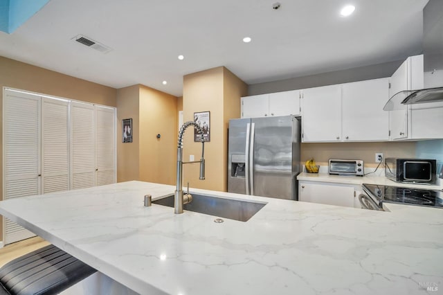 kitchen with a toaster, a sink, visible vents, appliances with stainless steel finishes, and light stone countertops