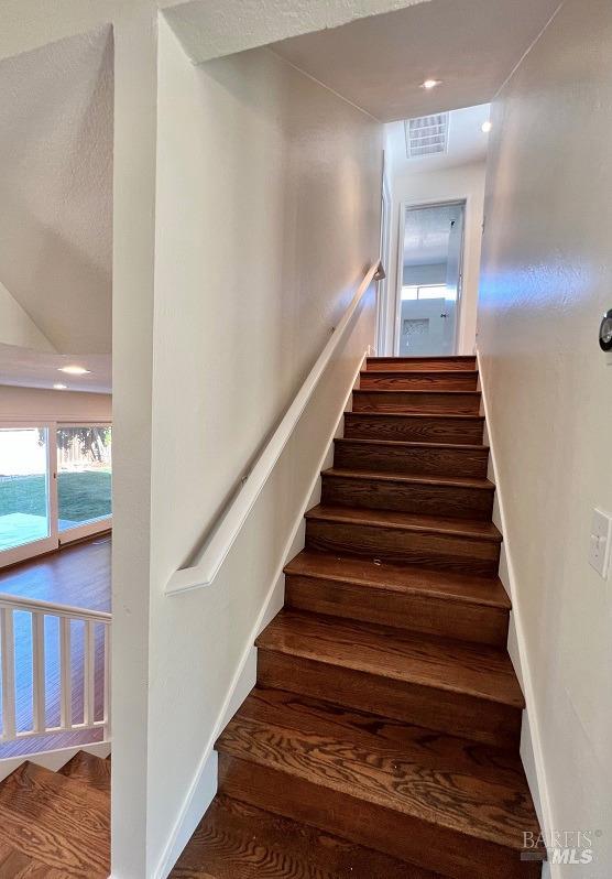 stairs with visible vents, baseboards, and wood finished floors