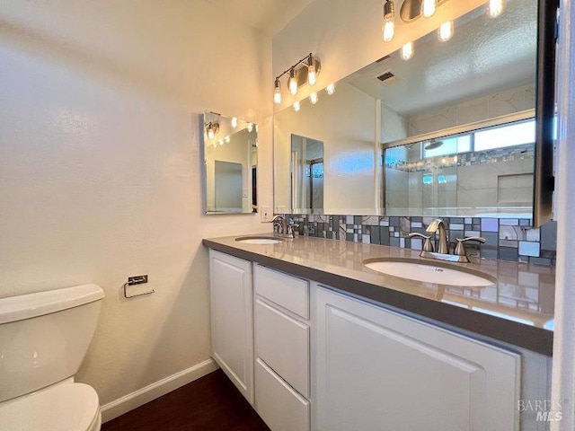 bathroom with toilet, double vanity, a sink, and visible vents