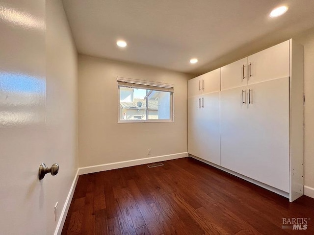 unfurnished bedroom featuring dark wood-type flooring, recessed lighting, visible vents, and baseboards