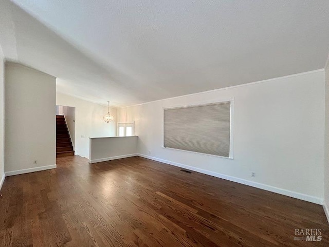 empty room featuring dark wood-style floors, stairs, baseboards, and vaulted ceiling