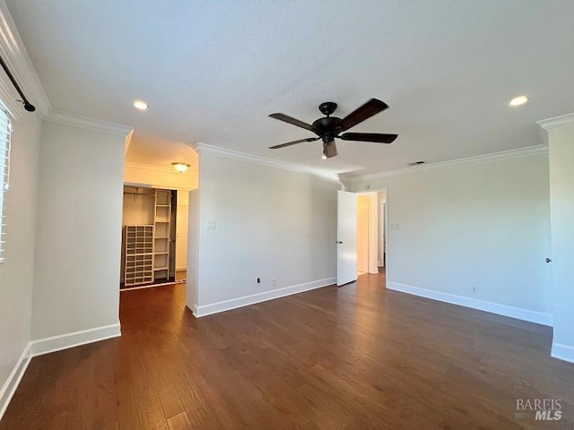 empty room featuring ornamental molding, dark wood-style flooring, baseboards, and a ceiling fan