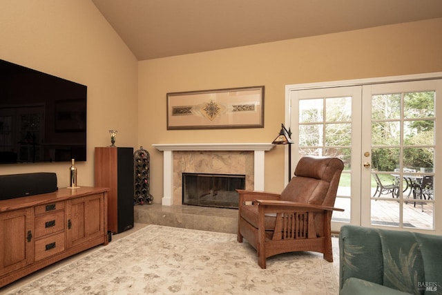 living area with light tile patterned floors, a premium fireplace, vaulted ceiling, and french doors