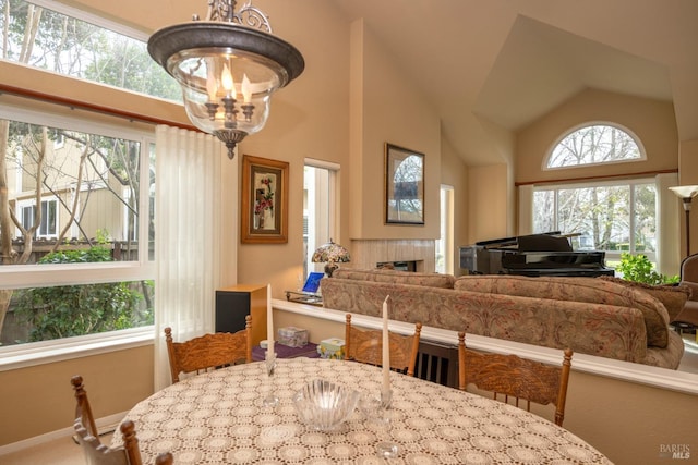 dining area with lofted ceiling, a fireplace, and an inviting chandelier