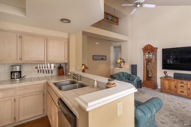 kitchen featuring tile countertops, stainless steel dishwasher, light brown cabinetry, a sink, and a peninsula