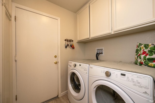 laundry area with light wood-type flooring, independent washer and dryer, and cabinet space