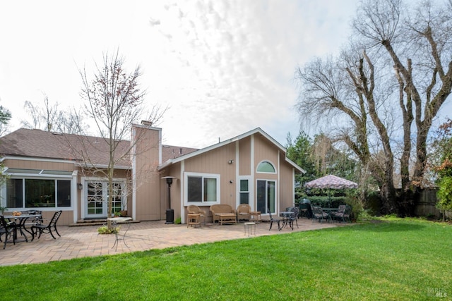 rear view of house with a yard, a chimney, and a patio