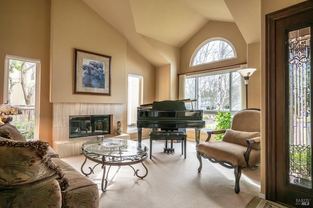 living area featuring high vaulted ceiling, a tile fireplace, and carpet