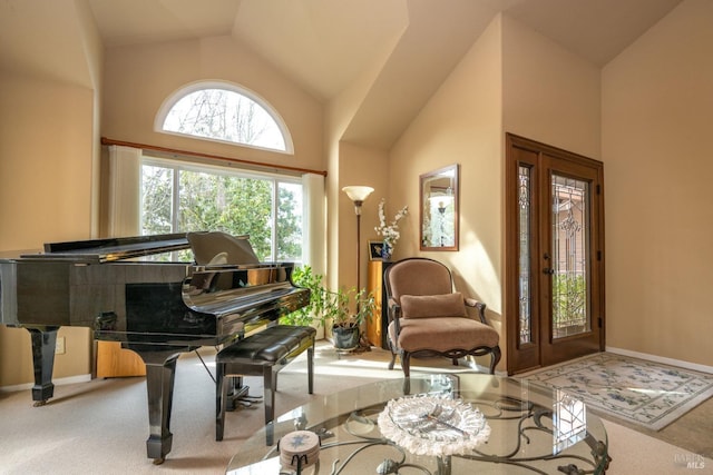 sitting room with baseboards, high vaulted ceiling, and light colored carpet