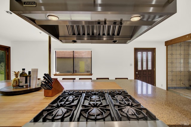 interior space featuring light stone countertops, cooktop, and exhaust hood